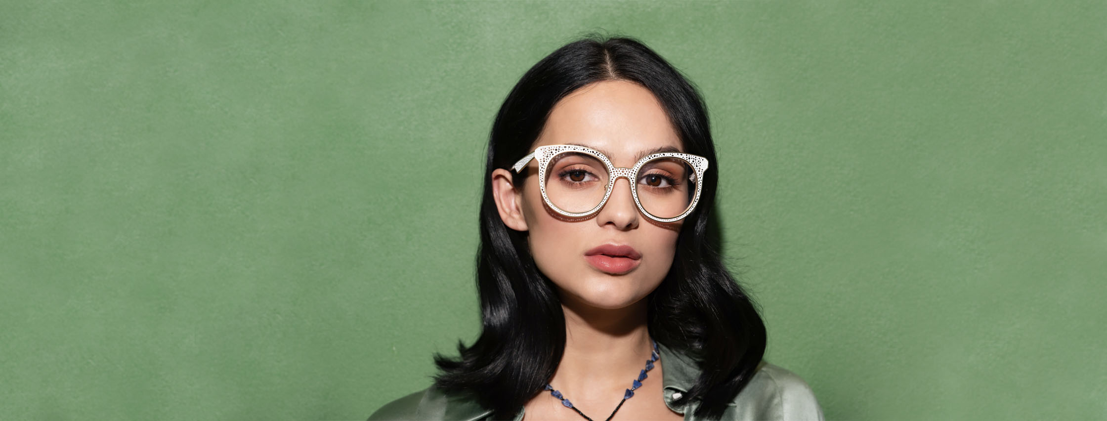 image of woman wearing oversized white metal frames against a green backdrop