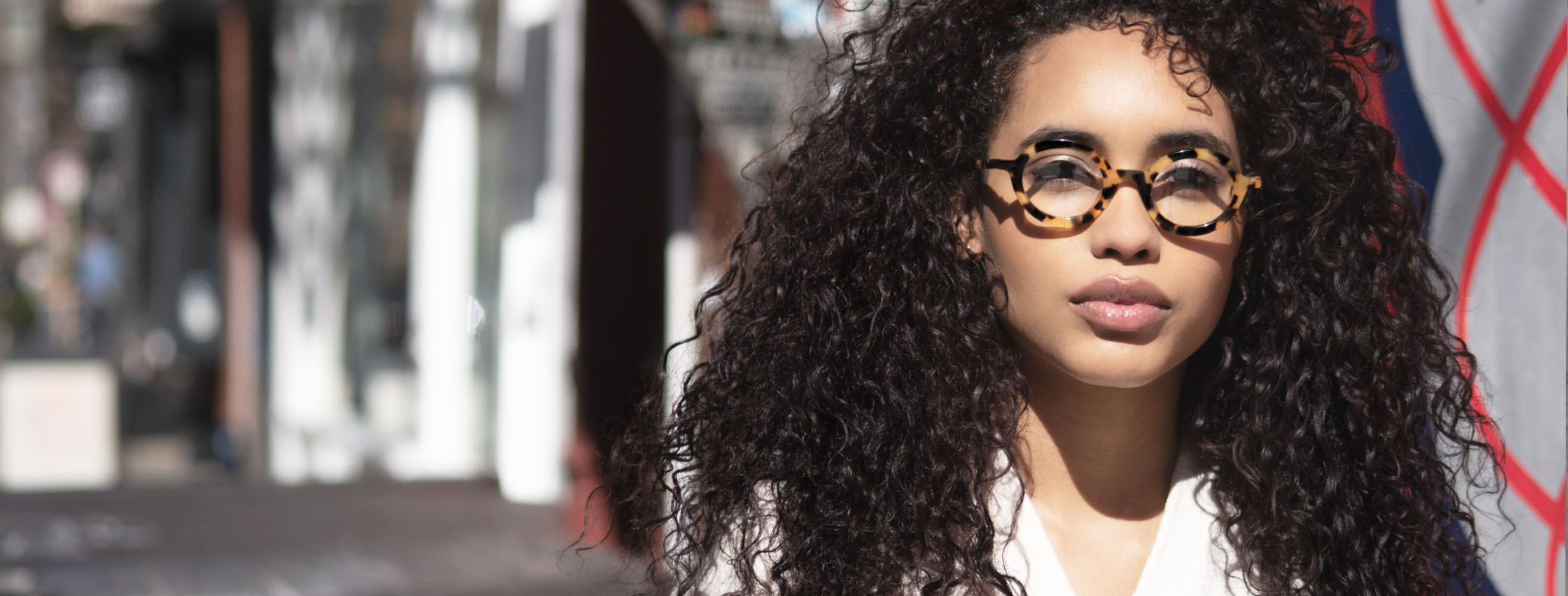 woman with curly brown hair wearing round tortoise acetate eyeglasses from vint and york